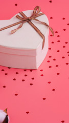 St. Valentine day background. Gift box with gold ribbon and lights on a pink background. Holiday background.