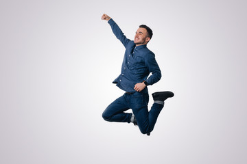 Fototapeta na wymiar Happy excited cheerful young man jumping and celebrating success over white background