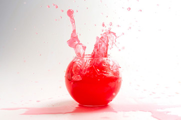 Splashes of red liquid in a glass globular vase