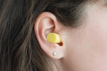 Woman's ear with an ear plug, noice reduce, noice pollution