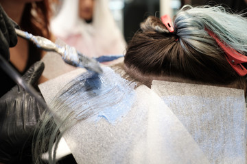 Una mujer recibe el tinte en una peluquería y se ven las manos de la peluquera