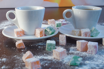 two white espresso cups, close-up, strewn with marmalade and powdered sugar