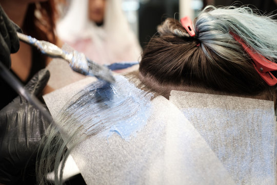 Una mujer recibe el tinte en una peluquer&iacute;a y se ven las manos de la peluquera