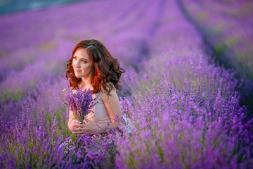beautiful bride in luxurious wedding dress in purple lavender flowers. Fashion romantic stylish woman with violet bouquet. Alluring slim girl in sunset over lavenda waiting for groom - Provence France