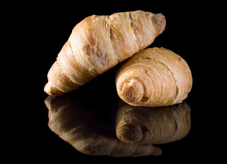 Croissants on black reflective background.