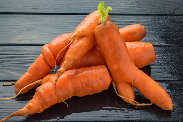 fresh ugly carrots on black wooden background