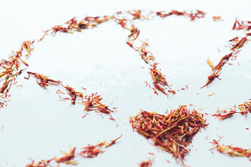 Selective focus close up Red Saffron in shape of circle with heart on white background. Delicate flower threads. Natural healthy spice. For cafe menu or catalog