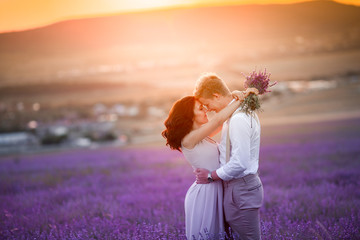 Young couple in love bride and groom, wedding day in summer. Enjoy a moment of happiness and love in a lavender field. Bride in a luxurious wedding dress.