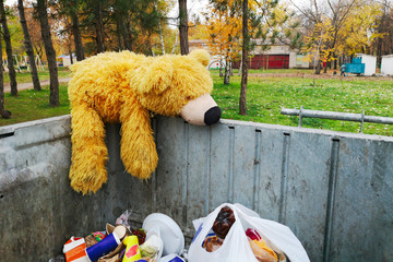 Abandoned teddy bear in the trash can. The symbol of leaving childhood, growing up
