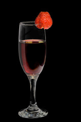 A glass of red wine with strawberries on a black background