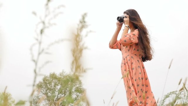 Beautiful girl in a dress. Photographs on the camera. Slow motion