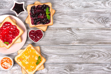 Delicious toasts with various sweet jams on grey background. Copyspace for your text, banner.