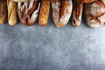Assortment of baked bread and bread rolls on stone table background