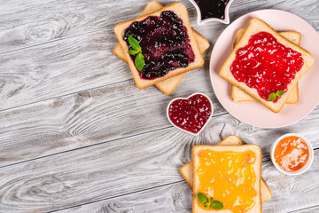 Delicious toasts with various sweet jams on grey background. Copyspace for your text, banner.