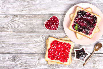 Delicious toasts with various sweet jams on grey background. Copyspace for your text, banner.