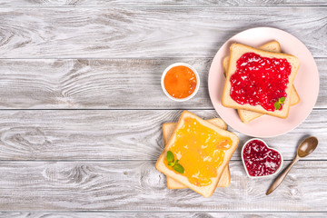 Delicious toasts with various sweet jams on grey background. Copyspace for your text, banner.