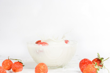 Splashes of milk from falling strawberries, white background.