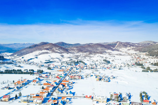 Croatian countryside landscape in winter, panoramic view of small town of Mrkopalj under snow in Gorski kotar, mountains in background 