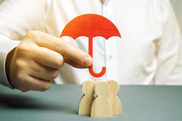 Boss holding a red umbrella and defending his team with a gesture of protection. Life insurance. Customer care, care for employees. Security and safety in a business team. Selective focus