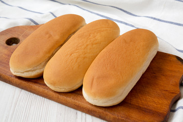 Hot dog buns on wooden board, side view. Closeup.