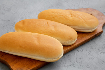 Hot dog buns on rustic wooden board on concrete background, low angle view. Closeup.