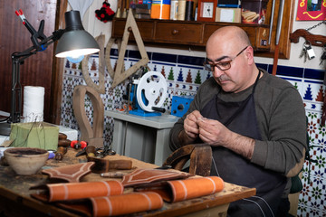 Fototapeta na wymiar craftsman working the leather in his small saddlery workshop