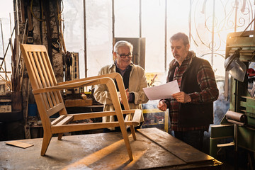 Fototapeta na wymiar Two craftsmen in their workshop working on an armchair frame