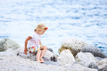 A little blond girl posing on the beach at the lake Lago di garda, Limone, Italy