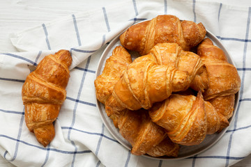 Fresh homemade golden croissants on grey round plate, top view. From above, overhead.