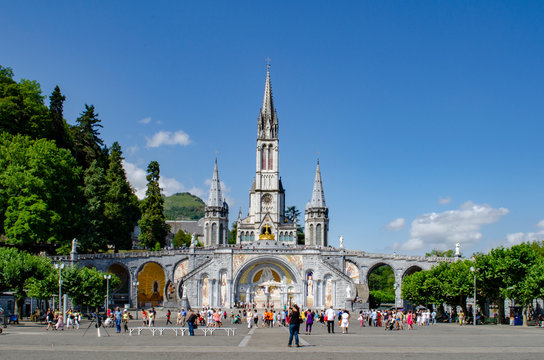 tourists walking in front of the cathedral of the sanctuary of Lourdes, France