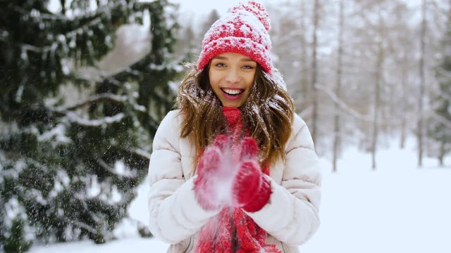 people, season and christmas concept - happy young woman in winter forest throwing snow
