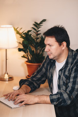 Portrait of a young male freelancer using a computer, working from a home office. Vertical image.