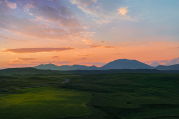 Beautiful sunset over the mountain. Green field.