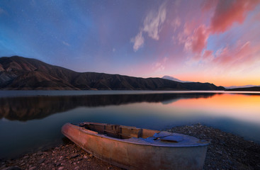 Naklejka na ściany i meble Beautiful sunset over the lake. Small boat on the lake.