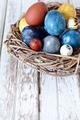 Dyed Easter vintage eggs with scuffs on a light gray background in a wicker basket. Stylish Background with easter eggs, modern. Happy Easter card. 