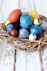 Dyed Easter vintage eggs with scuffs on a light gray background in a wicker basket. Stylish Background with easter eggs, modern. Happy Easter card. 