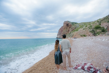 A beautiful romantic couple have a rest  on a beach dressed in warm clothes