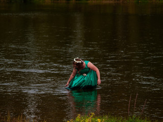 Portrait of a cheerful young woman in a river dressed with a green party dress