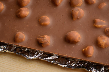 Bar of milk chocolate with nuts covered with foil.