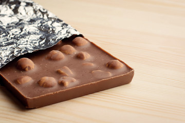 Tasty chocolate with nuts, hazelnuts lays on wooden table