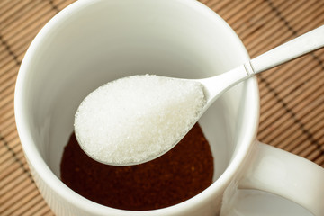 Pouring some sugar to the cup with coffee. Adding sugar to the coffee. Making coffee at home