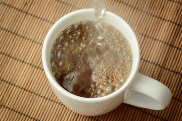 Pouring boiling water to the cap with instant coffee. Making strong coffee in the morning.