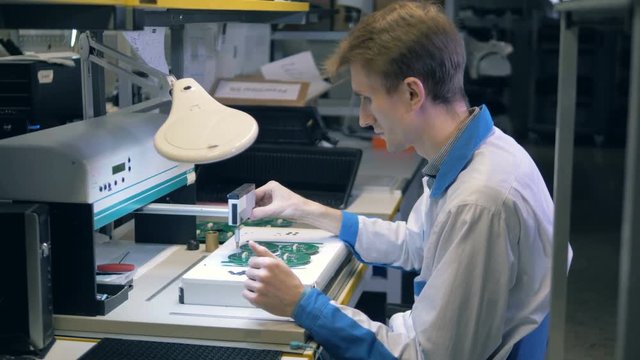 Laboratory worker is using a machine to assemble boards