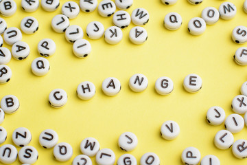 Word CHANGE made of plastic blocks on a yellow background with many letters around