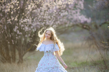 Fototapeta na wymiar Sweet woman in a beautiful dress, walking through the park with flowers in hands