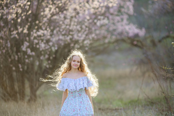 Fototapeta na wymiar Sweet woman in a beautiful dress, walking through the park with flowers in hands