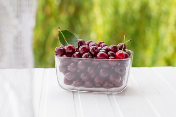 Fresh cherries in glass containers on the table by the window.
