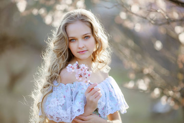 Blond curly woman with long hair walk in blooming garden