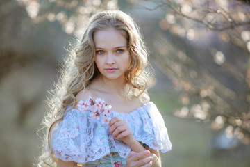 Blond curly woman with long hair walk in blooming garden
