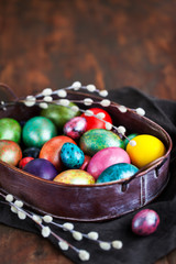 Fototapeta na wymiar Easter colorful painted eggs and willow on dark rustic background, spring holiday concept